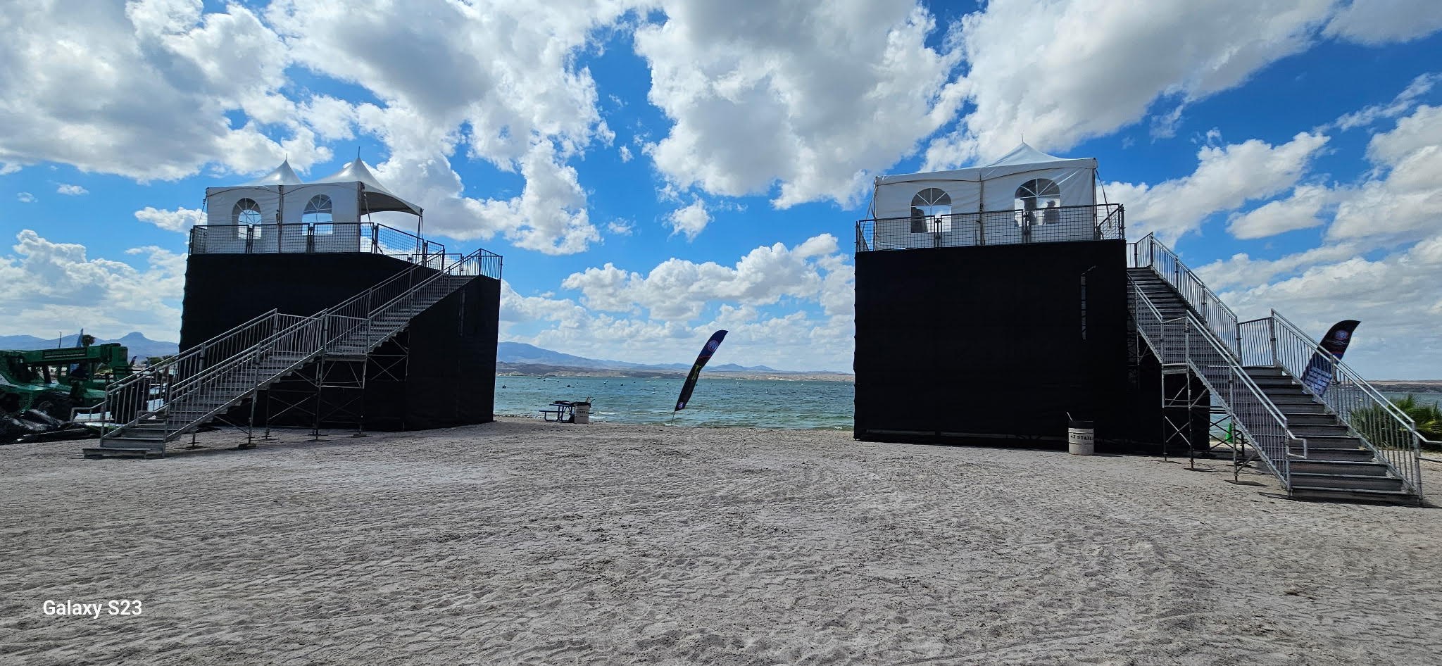 Two elevated covered event platforms installed beside a lake